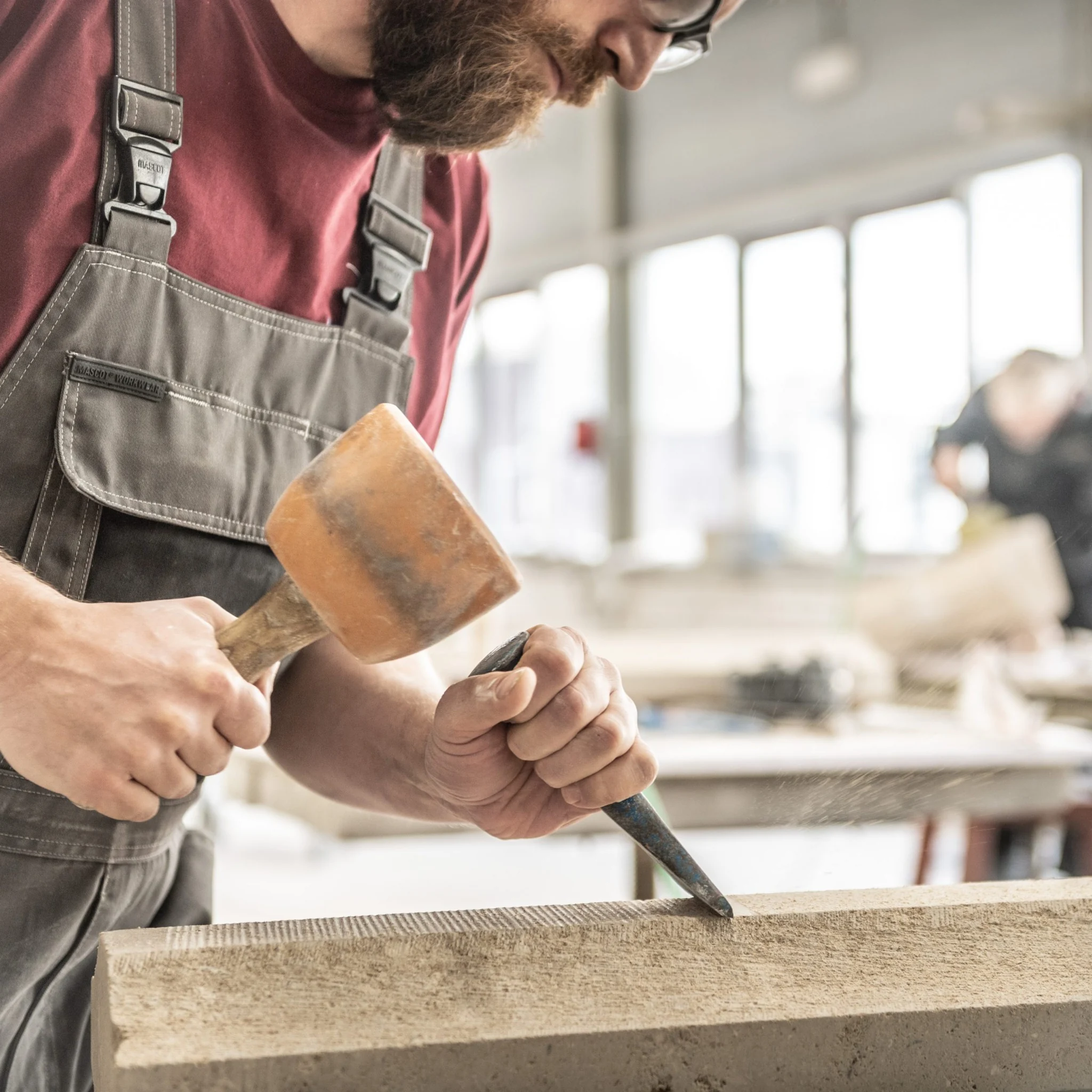 Een ambachtsman bewerkt hout met een beitel en houten hamer in de werkplaats