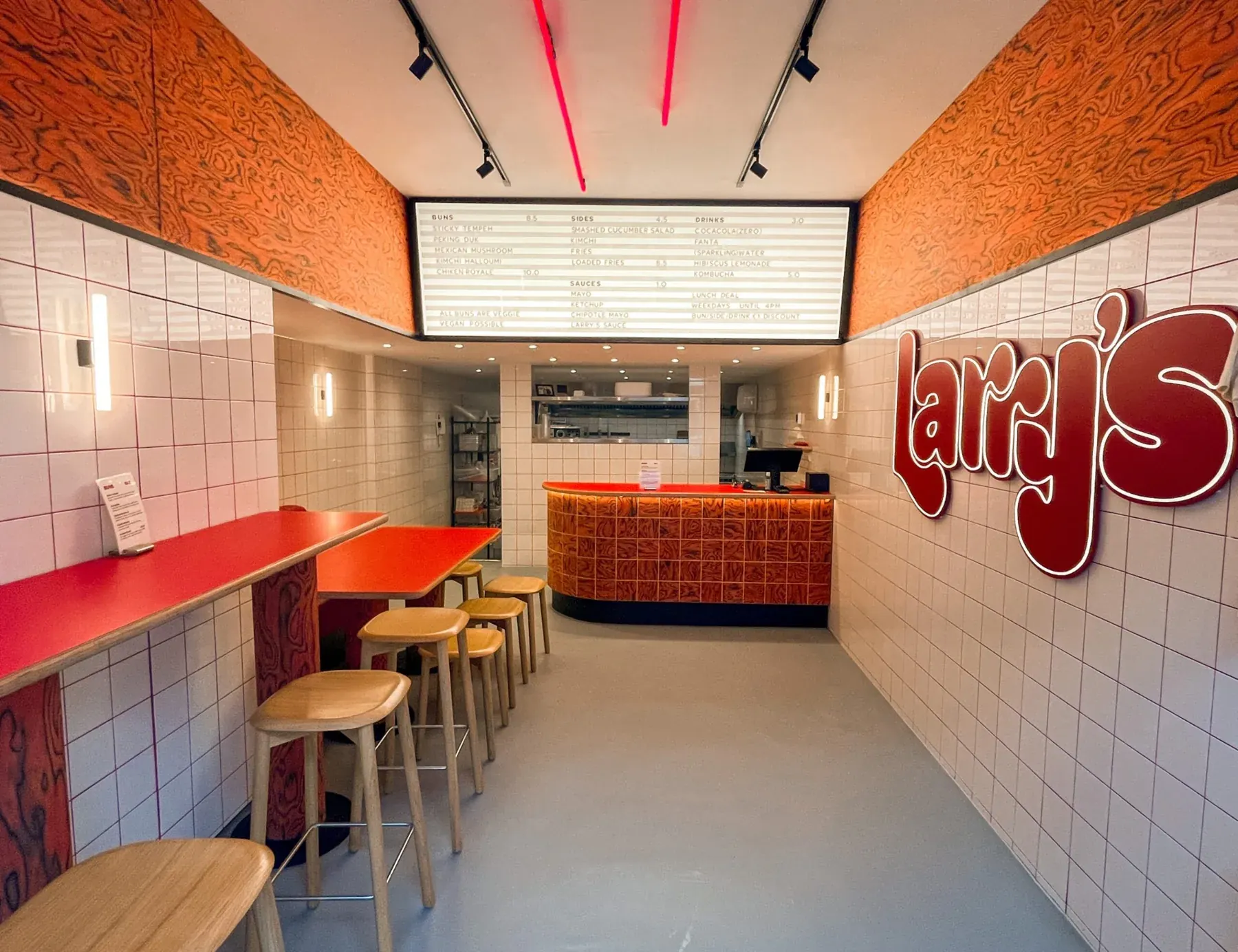 Interieur van Larry’s met tegelwand, zitplaatsen en rode accenten