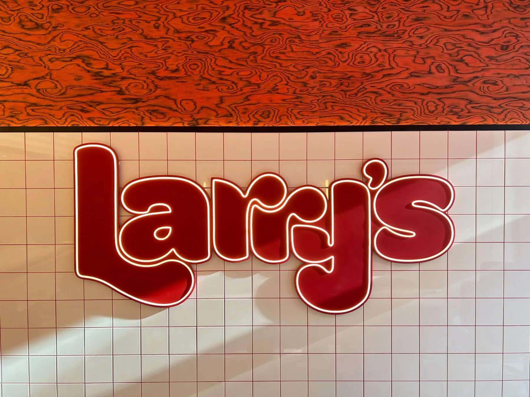 Detail van het rode Larry’s woordmerk op de tegelwand