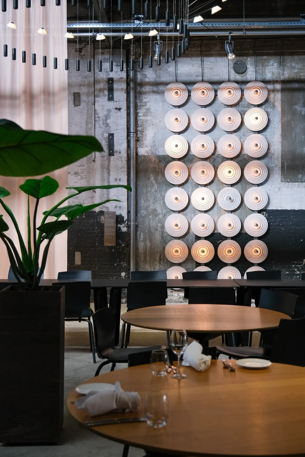 The Ripple als lichtwand in een interieur met tafels en een plant