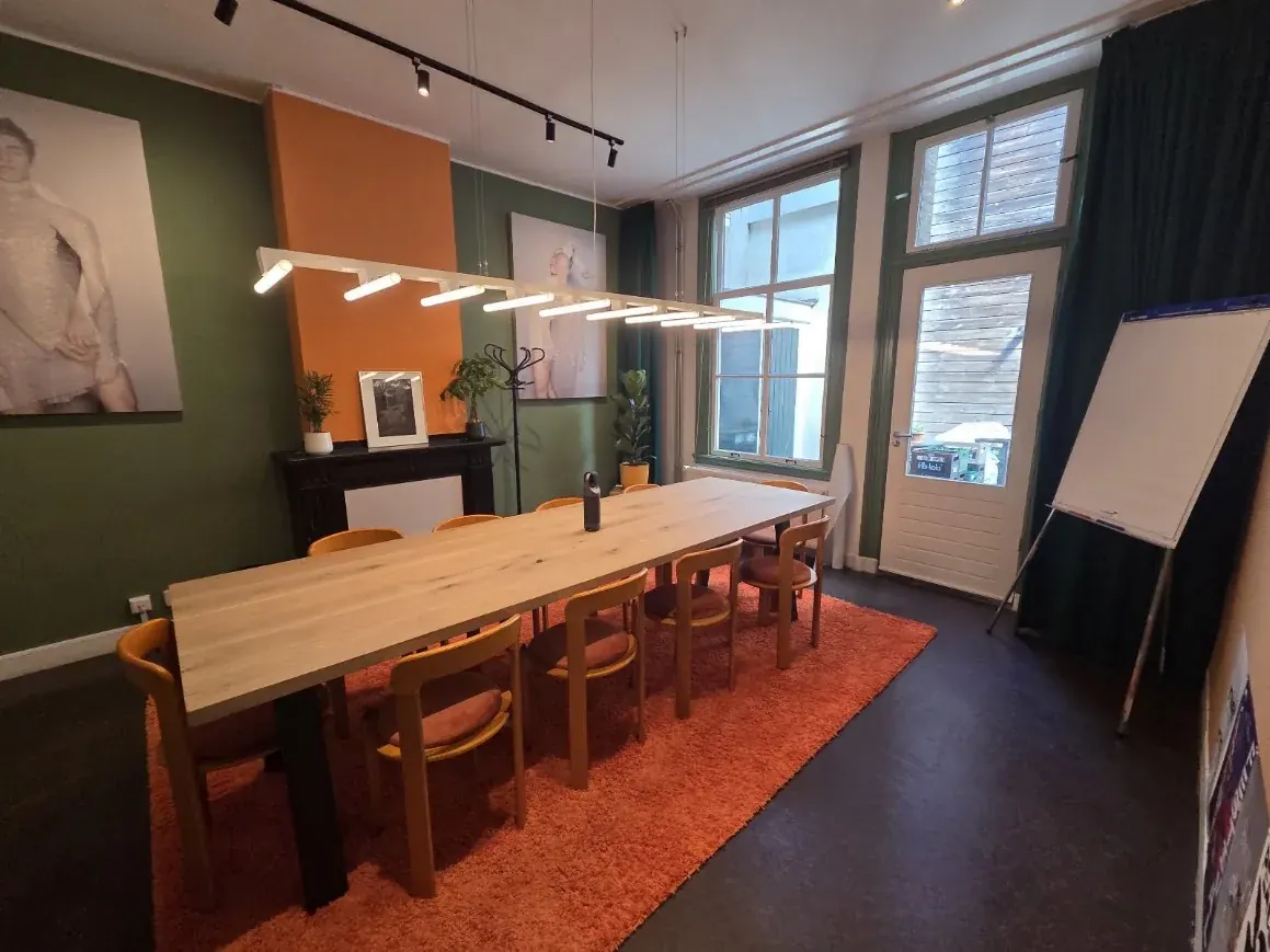 Lange werktafel met stoelen in een lichte werkruimte